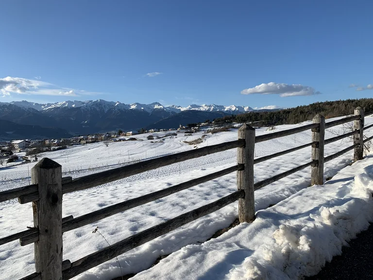Paesaggio innevato con una staccionata, il borgo e le montagne